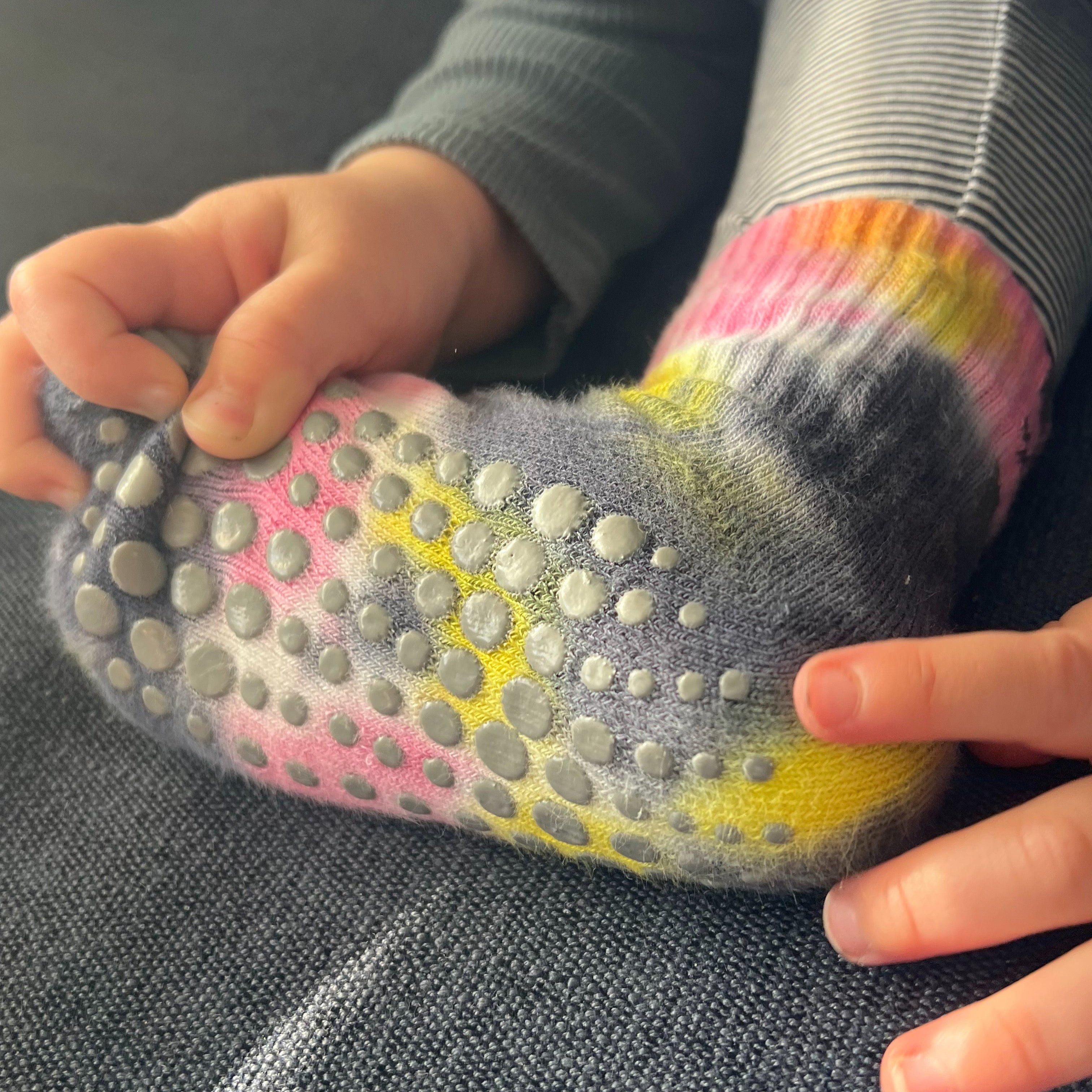 A toddler wearing grip socks and touching the spots with his fingers.
