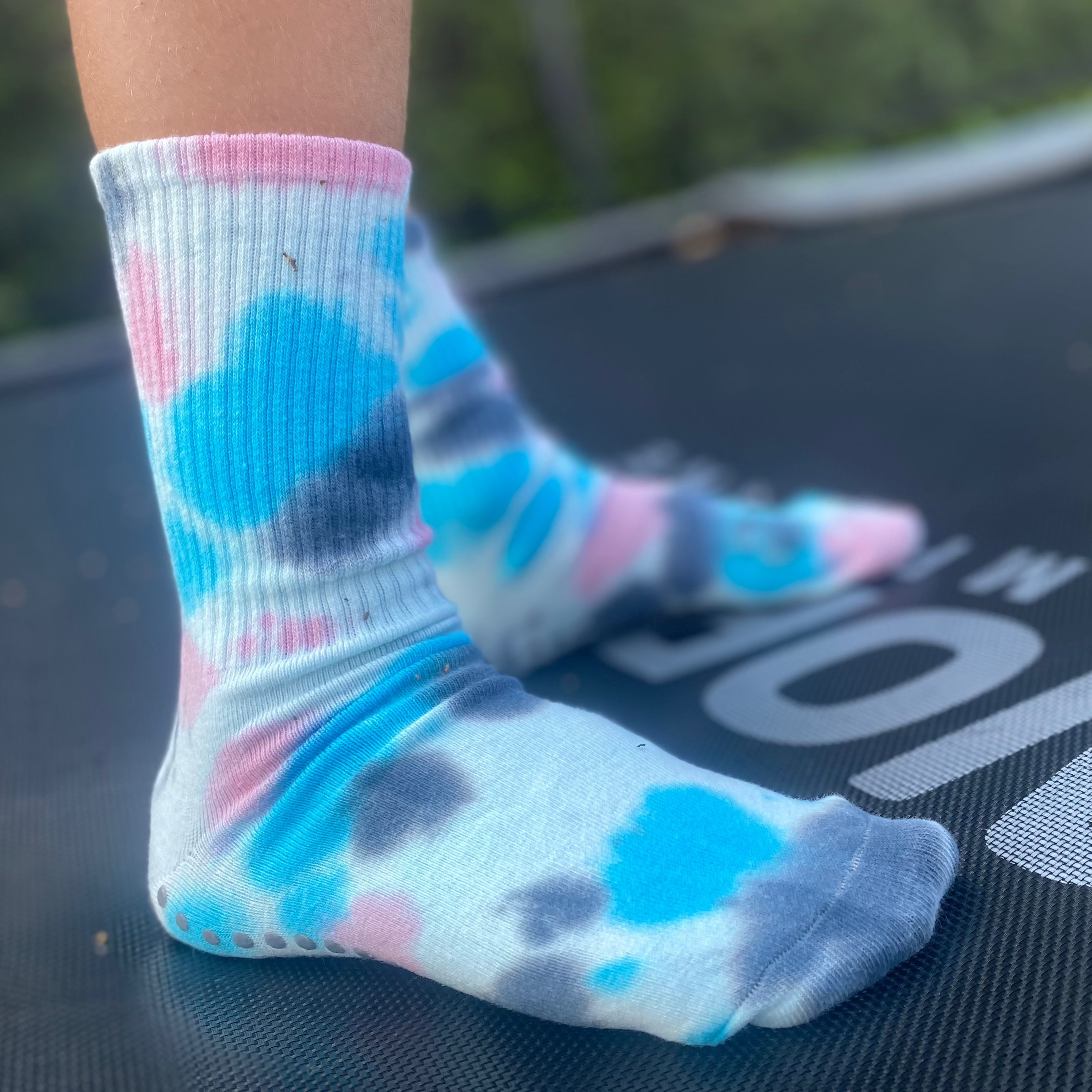 A child wearing tie-dye socks on a trampoline.
