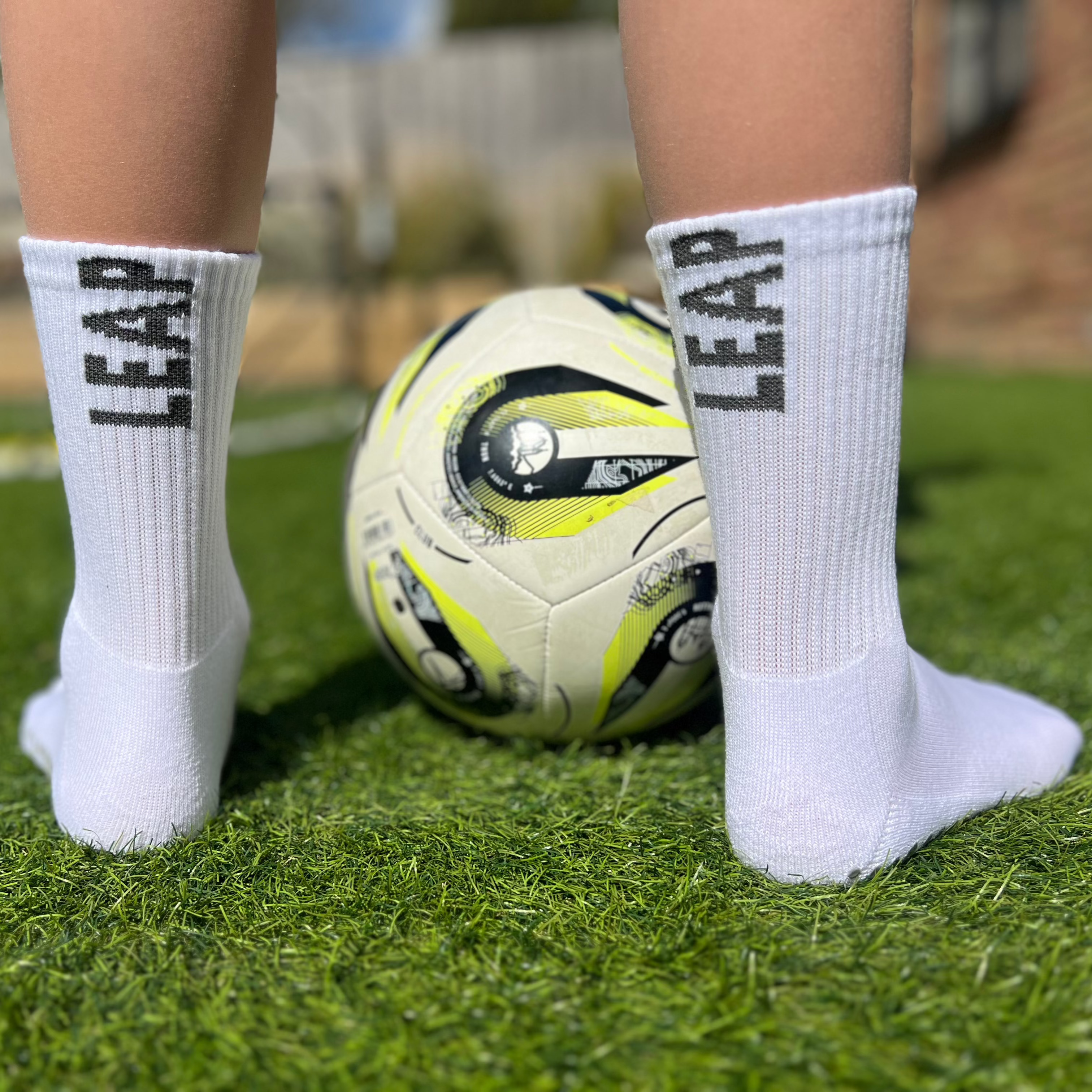 A child standing with a football showing the back view of Leap ankle socks.