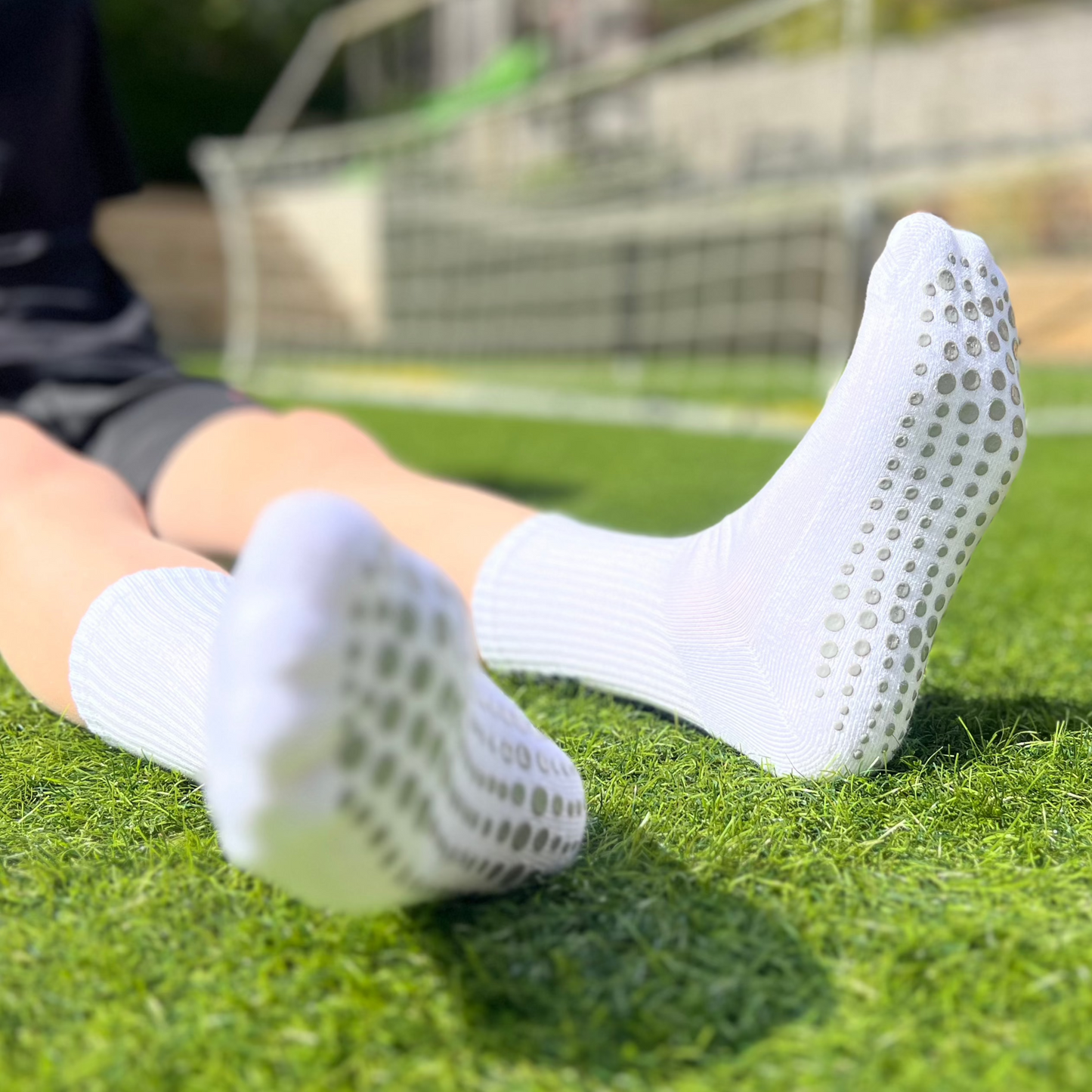 A child sitting down wearing football grip socks showing undersoles.