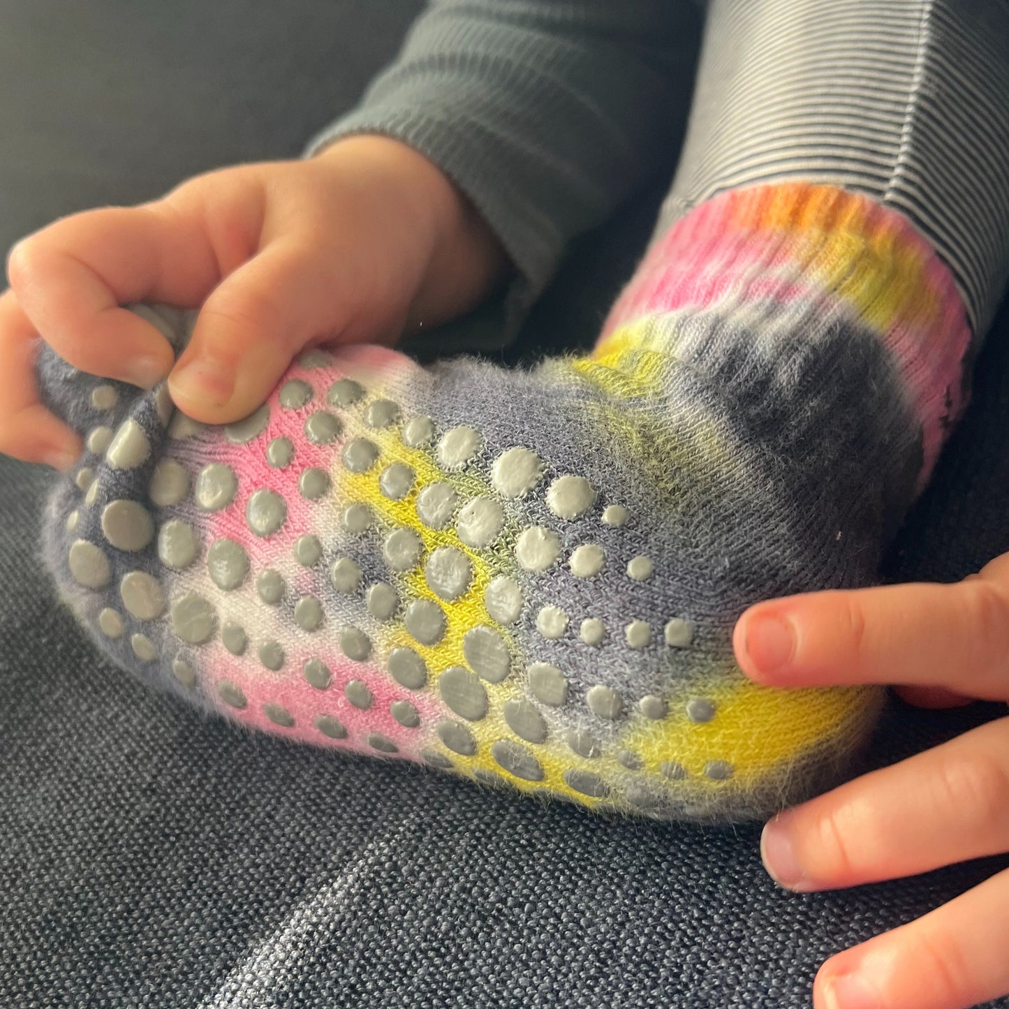 A toddler wearing grip socks and touching the spots with his fingers.