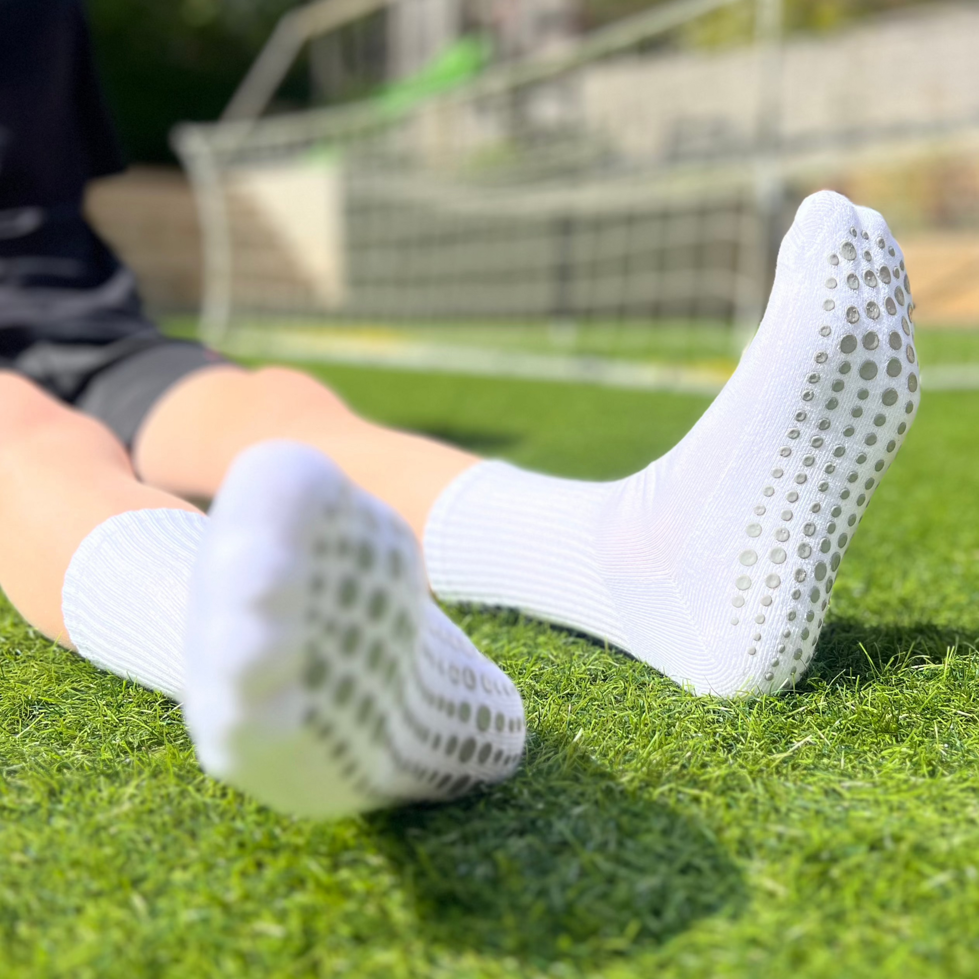 A child sitting down wearing football grip socks showing undersoles.